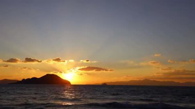 Sonbaharda Ege Denizi üzerinde bulutlu bir günde muhteşem bir gün batımı. Bulutların arasından süzülen güneş ışınlarıyla hızlandırılmış bir video..