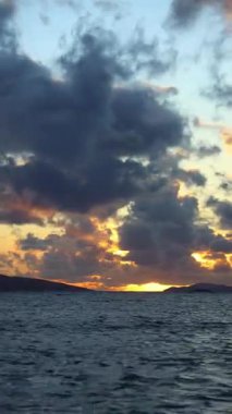 Sonbaharda Ege Denizi üzerinde bulutlu bir günde muhteşem bir gün batımı. sosyal medya için dikey video.