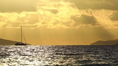 Denizde yelkenli. Denizin üzerinde deniz manzaralı altın gün doğumu. Gündoğumunda yat gezintisi. Güzel bir yelkenli ile deniz manzarası. Yelkenliyle turizm turizmi.