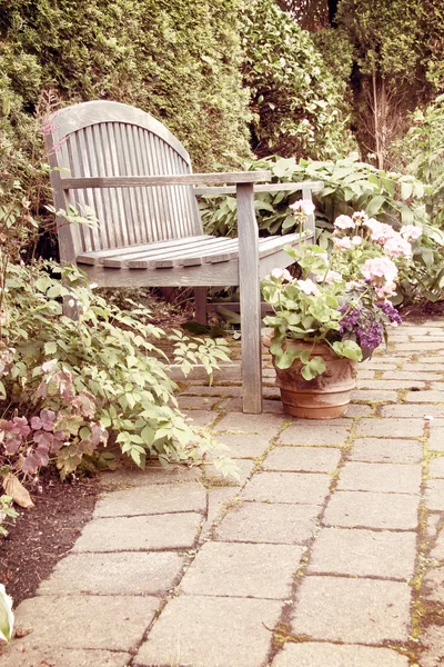 Tuin bankje met ingemaakte geraniums. — Stockfoto