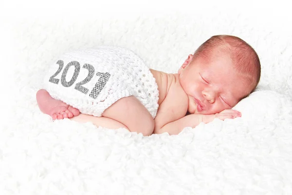 新生児は 2021年に編んだオムツカバーで白い毛布の上で眠っています 明けましておめでとう — ストック写真