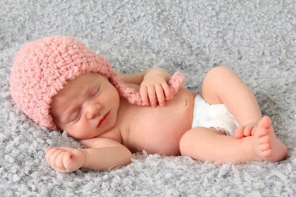 Pasgeboren babymeisje slaapt in roze gebreide muts — Stockfoto