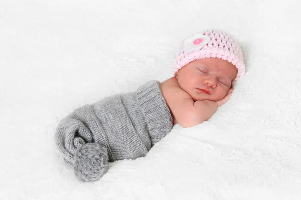 Bebé recién nacido niña en rosa sombrero de punto durmiendo — Foto de Stock