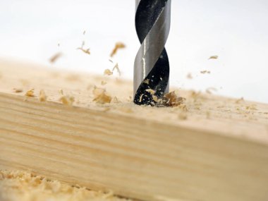 Beyaz zemin üzerinde uçan talaş ile tahtaya delik açmak