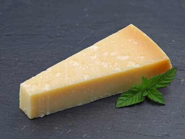 Bir parça parmigiano peyniri, yeşil yapraklı parmesan peyniri.