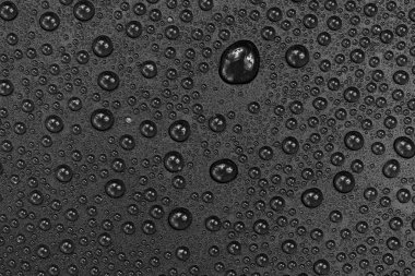 Siyah arkaplan dokusuna su damlaları. Su damlalarıyla kaplı koyu renk bir arka plan camı. Sudaki gri kabarcıklar