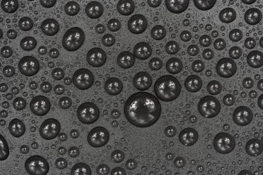 Siyah arkaplan dokusuna su damlaları. Su damlalarıyla kaplı koyu renk bir arka plan camı. Sudaki gri kabarcıklar