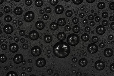 Siyah arkaplan dokusuna su damlaları. Su damlalarıyla kaplı koyu renk bir arka plan camı. Sudaki gri kabarcıklar