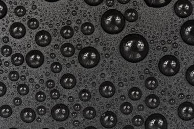 Siyah arkaplan dokusuna su damlaları. Su damlalarıyla kaplı koyu renk bir arka plan camı. Sudaki gri kabarcıklar