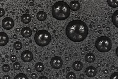 Siyah arkaplan dokusuna su damlaları. Su damlalarıyla kaplı koyu renk bir arka plan camı. Sudaki gri kabarcıklar