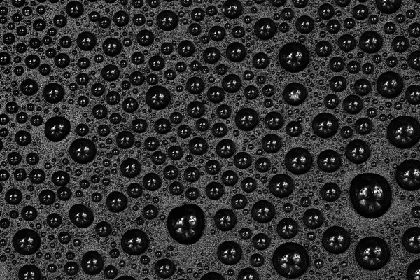 Water drops on black background texture. Dark backdrop glass covered with drops of water. gray bubbles in water