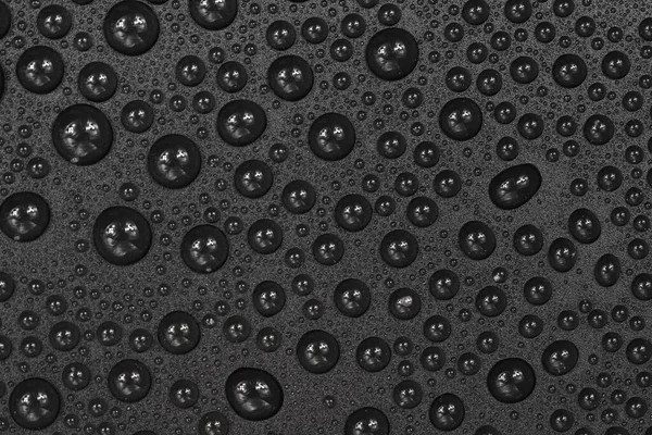 Water drops on black background texture. Dark backdrop glass covered with drops of water. gray bubbles in water