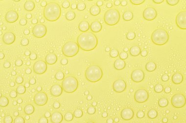 Sarı arkaplan dokusuna su damlaları. Arkaplan camı su damlalarıyla kaplı. Suda sarı kabarcıklar. bira dokusu