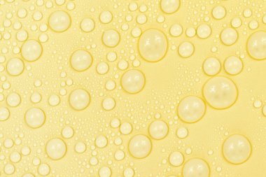 Sarı arkaplan dokusuna su damlaları. Arkaplan camı su damlalarıyla kaplı. Suda sarı kabarcıklar. bira dokusu
