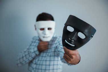 Adam gri sırtüstü elleri siyah maskeli beyaz yüzlü.