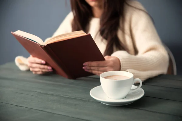 woman reading book with coffee on des