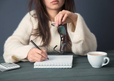 Des üzerinde not defteri olan kadın el gözlükleri