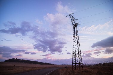 Gün batımında yol ve yüksek voltaj kulesi.