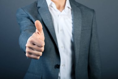 İşadamı başparmağı gri duvarda.