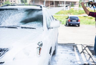 Erkek işçi araba temizliyor.