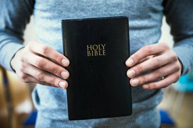 Genç adam kutsal kitabı tutuyor.