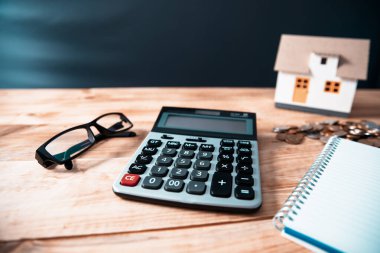tablo üzerinde hesap makinesi olan ev modeli ve sikkeler