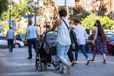Bebek arabalı bir kadın sokakta yürüyor.