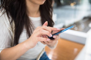 Kadın el ele tutuşup akıllı telefon kullanıyor.