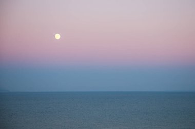 # Renkli güneşin altında denizin üzerinde ay #