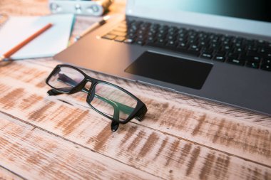 Masada dizüstü bilgisayarı ve not defteri olan gözlükler.