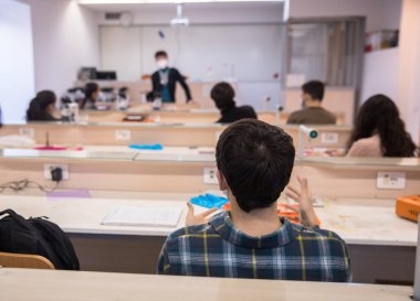 Erkek profesör sınıftaki öğrencilere dersi açıklar.