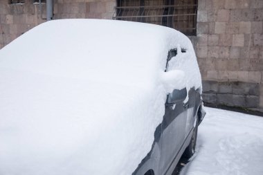 Karlı bir yolda kar altında bir araba.