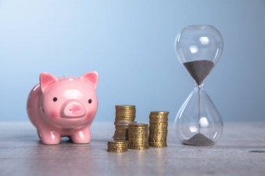 Üzerinde bozuk para ve kum saati olan kumbara.