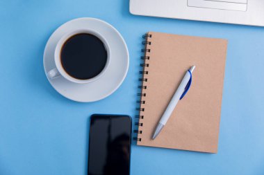 Dizüstü bilgisayarı, kahve fincanı ve not defteri olan ofis masası.