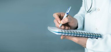 Genç doktor elinde not defteriyle kalem tutuyor.