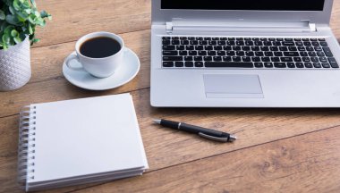 Not defterli bilgisayar ve çalışma masasında çiçekli kahve.