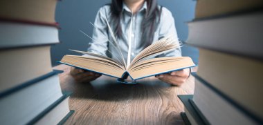Kadın masada oturuyor ve kitap okuyor.
