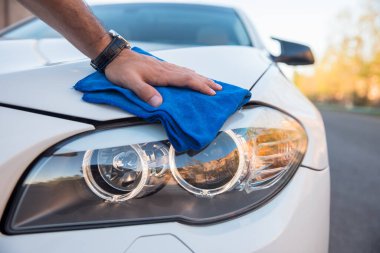 Genç adam pıhtılı arabayı temizliyor.