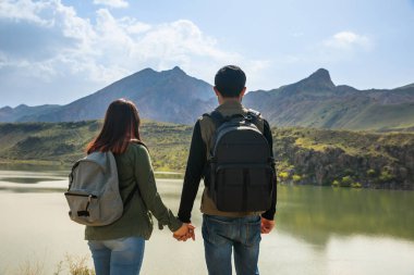 Genç çift göl kenarında el ele.