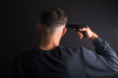 Depresif genç adam, elinde silah tutuyor.