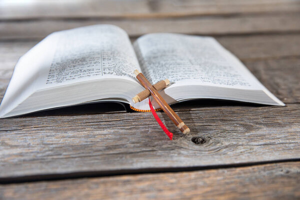 wooden cross on the open Bible on tabl