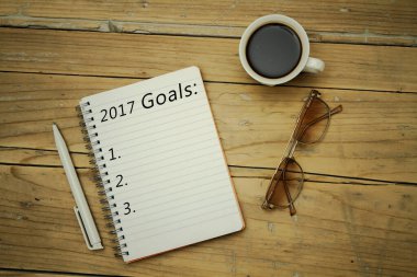 Üst görünüm 2017 gol listesi, defter, özellikler, ahşap masa üzerinde bir fincan kahve.