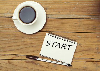 Ahşap arka planda bir defter ve kahve.