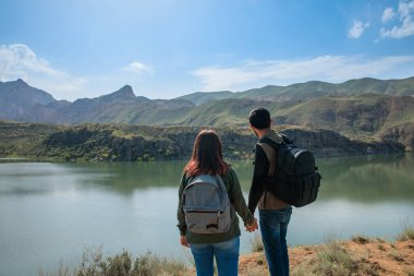 Çift yürüyüş yapıyor ve göl manzarasının tadını çıkarıyor.