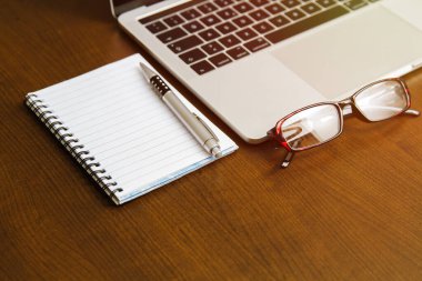 Ofis masası, işyeri, dizüstü bilgisayar, kağıt ve kalem ahşap masa üzerinde (gözlük))