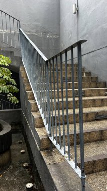 Çağdaş bir beton merdiven ve parlak metal parmaklıklar, şehir keşfi ve mimari tasarımı temsil ederek gözü yukarı kaldırır..