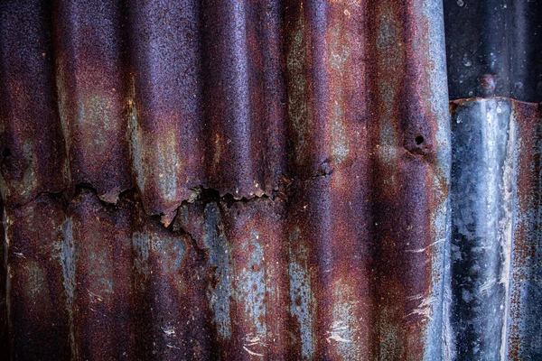 Damaged galvanized iron sheet wall on old warehouse. Detail view of old rusty corrugated metal sheet.