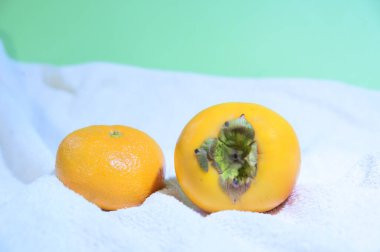 Beyaz havluyla mandalinalı olgun hurma, yakın görüş. 