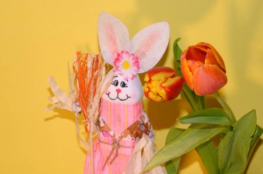 Işık arka planda laleleri olan dekoratif Paskalya tavşanı, yakın görüş, mutlu Paskalya konsepti 