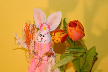 Işık arka planda laleleri olan dekoratif Paskalya tavşanı, yakın görüş, mutlu Paskalya konsepti 